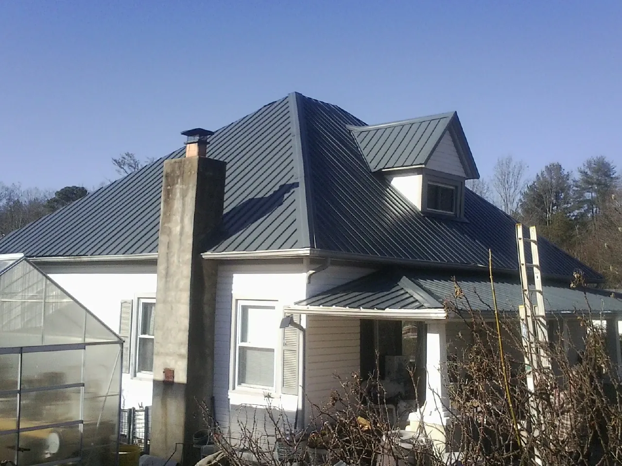 Dark blue standing seam metal roof on a white farmhouse with dormer — Slate & Tile Roof Repair by Roofing Brothers in Haverford