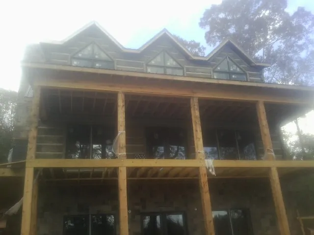 Dormers and porch framing on a large log home under construction — Roof Coating work by our crew in Haverford