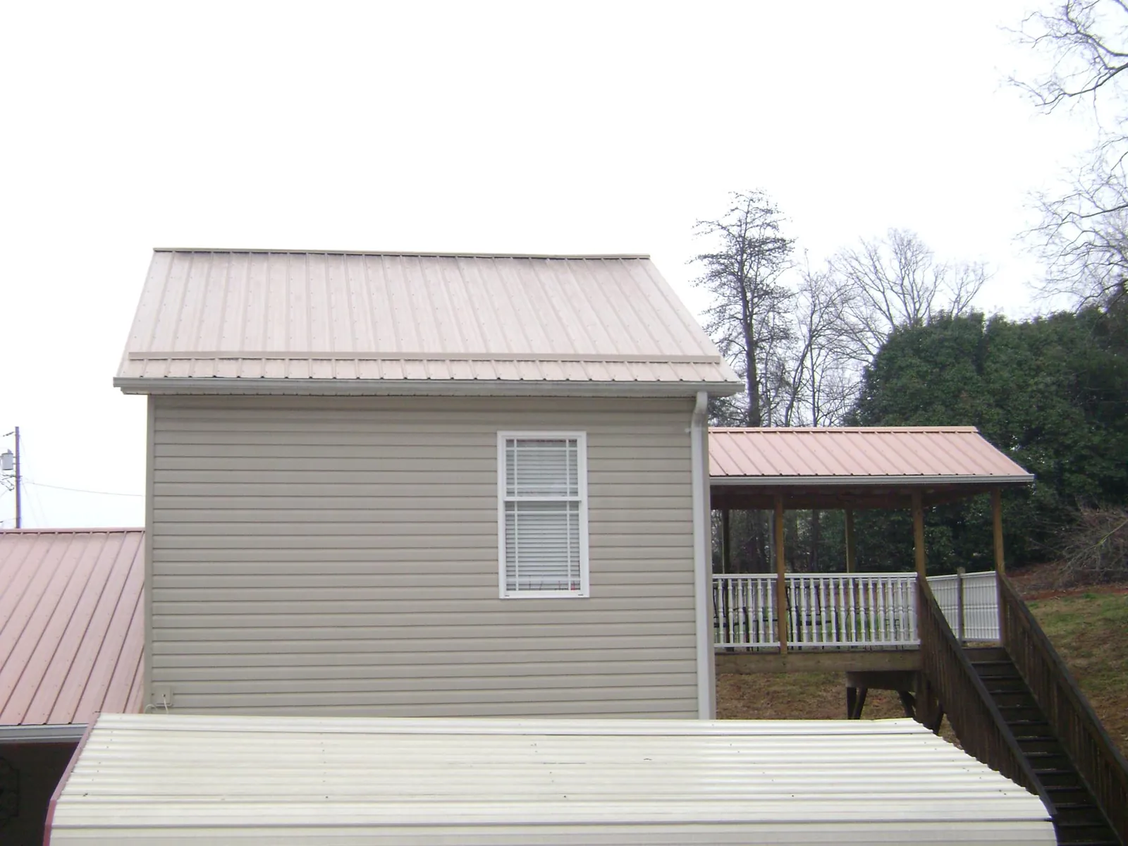 Tan metal roofs on a two story addition and attached porch, from a Roof Replacement job in Haverford