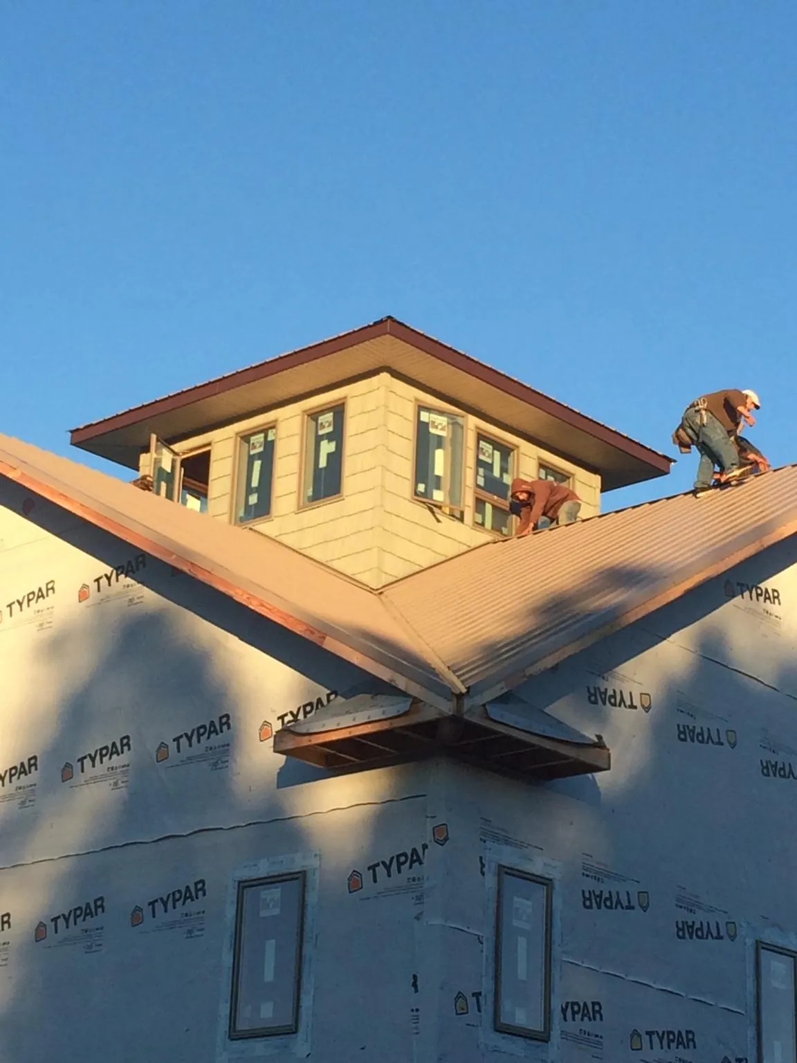 Roofers working around a rooftop cupola on a new metal roof at sunset — Roof Waterproofing in Haverford by Roofing Brothers